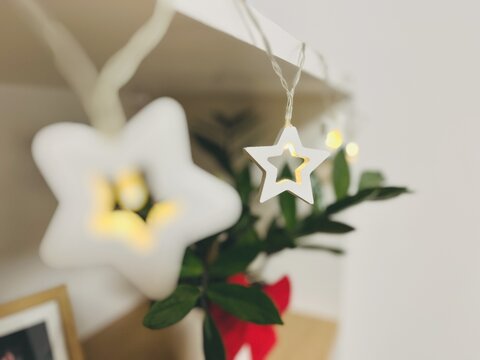 Close-up of illuminated Christmas star shaped string lights hanging on a shelf in a living room