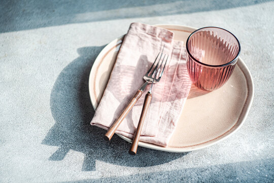 Close-up of a simple pink place setting on a table in sunlight