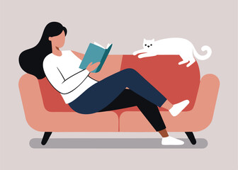 A woman relaxes on a couch engrossed in a book