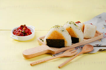 노란색 테이블 위에 담긴 김밥과 밥 위에 고추장 양념이 더해진 요리의...