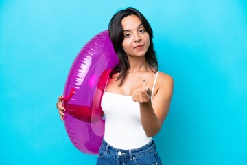 Young hispanic woman holding air mattress donut isolated on blue background making money gesture
