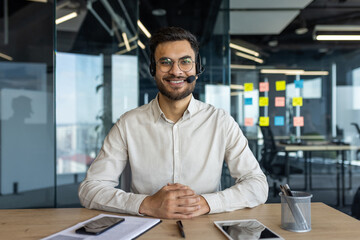 Mature man wearing a headset and working at desk in office. The professional appears engaged and...