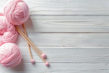 A wooden table with a pink ball of yarn and two knitting needles