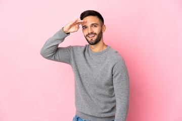 Fototapeta premium Young caucasian man isolated on pink background looking far away with hand to look something