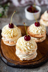 Almond cakes with cherries. Brownies with buttercream for dessert. Small cakes for breakfast on a gray background. Vertical photo.