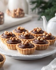 A platter of chocolate tartlets topped with walnuts, perfect for dessert or special occasions.