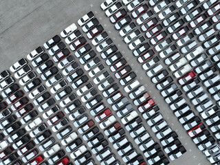 Aerial view of new cars stock at factory parking lot. Above view cars parked in a row. Automotive...