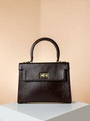 Beautiful dark brown leather bag for women, set on a white box with a light brown background, elegant and fashionable design. Perfect for modern women's style.