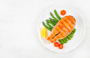 Grilled salmon steak with asparagus and tomatoes cherry on a white plate. top view. copy space