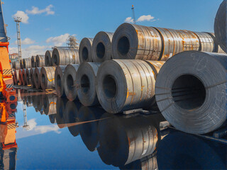 Stacks of steel sheet rolls in the port, cold rolled steel rolls. A roll of sheet iron. Hot rolled steel rolls are stored outdoors. Rolls of steel sheet. Sheet metal in the port. 
