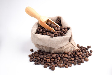 Sack and wooden scoop with roasted coffee beans isolated on white background.