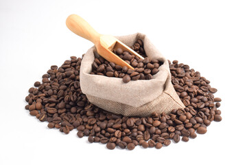 Sack and wooden scoop with roasted coffee beans isolated on white background.