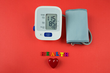 red heart and electronic tonometer on a red background.
