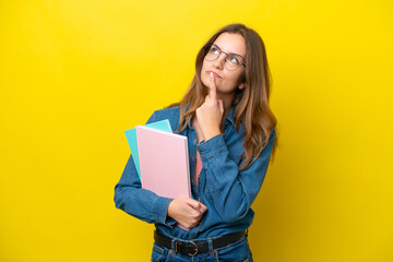 Young student caucasian woman isolated on yellow background having doubts while looking up