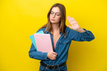 Young student caucasian woman isolated on yellow background making stop gesture and disappointed