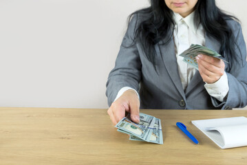 Business woman with notepad, calculator and dollars sitting at table. Crop photo.