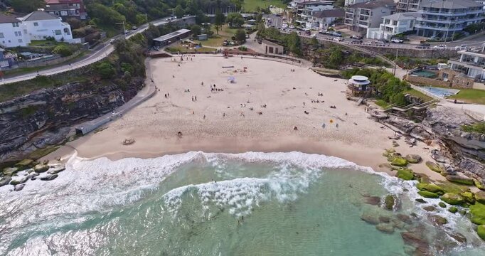  Bronte Beach, Sydney, Australia close-up aerial view. Turquoise waves gently roll onto the golden sand, creating a picturesque coastal scene. Focus on the shoreline and the textures of the sand.
