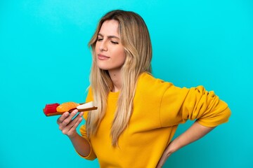 Young Uruguayan woman holding sashimi isolated on blue background suffering from backache for having made an effort