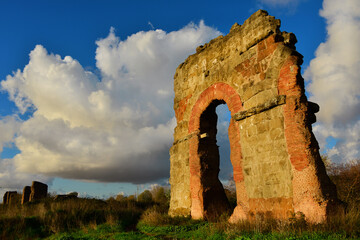 Ancient roman aqueduct beautiful arches ruins in Rome public park at sunset