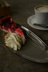 kuchenstück mit sahne und einem kaffee im hintergrund