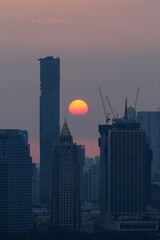 Fototapeta premium Bangkok skyline during a dramatic sunset with construction cranes and skyscrapers, Thailand