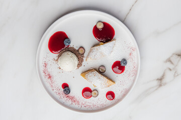 Apple strudel with powdered sugar, accompany a scoop of vanilla ice cream, drizzled with berry...