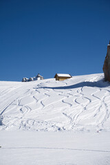 Small isolated retreat in the snow-capped mountains of the Dolomites in Italy on a sunny day with blue skies. Ideal destination for lovers of winter sports and nature
