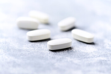 Arginine alpha-ketoglutarate (AAKG) tablets. Bodybuilding food supplements on wooden background. Soft focus. Close up. Copy space.