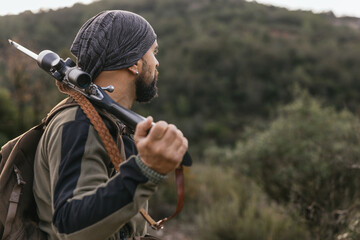 Hunter walking through forest carrying rifle on shoulder