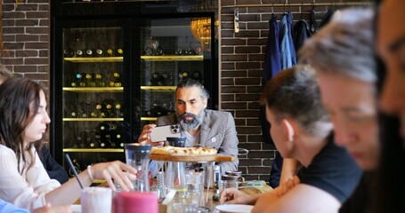 Blogger engaging with followers on phone while sitting with friends at cozy restaurant. Scene emphasizes social media connection, informal atmosphere, and audience interaction. Blogger Concept