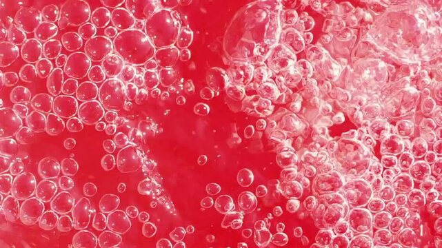 Bubbles forming in a vibrant red liquid during a refreshing drink preparation in a kitchen setting
