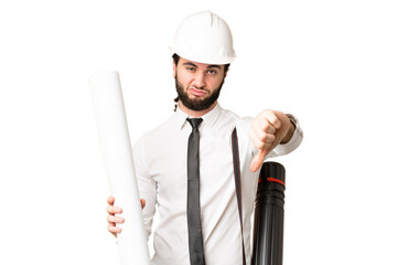 Young architect man with helmet and holding blueprints over isolated chroma key background showing thumb down with negative expression