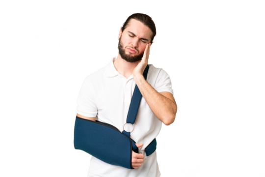 Young handsome man with broken arm and wearing a sling over isolated chroma key background with headache