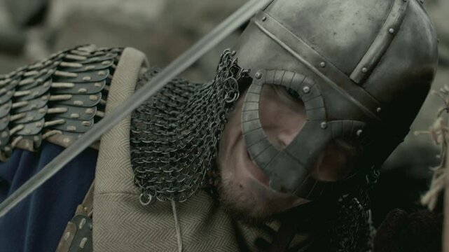 Brutal medieval warrior armored in chainmail and helmet, holding shield and stabbing enemy with sword in battle