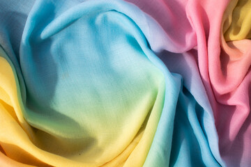 Gradient yellow blue pink and green fabric wavy spiral crumpled background texture with copy space.