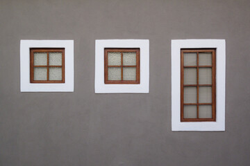 Three closed windows on a grey wall with white borders and blank space for text