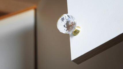 Elegant clear, acrylic, glass or crystal cabinet handle enhances a modern kitchen cabinet design with stylish hardware. Photo. Close-up
