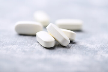 Arginine alpha-ketoglutarate (AAKG) tablets. Bodybuilding food supplements on wooden background. Soft focus. Close up. Copy space.