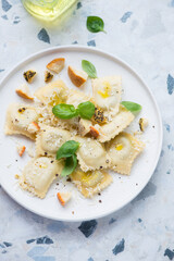 Ravioli with different types of cheese and fresh basil, vertical shot on a white and blue granite background, high angle view