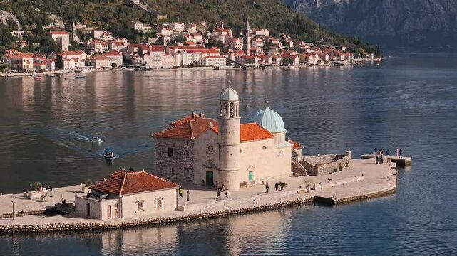 Drone footages - Our Lady of The Rock and Perast in Montenegro on a sunny day. Famous travel destination. Long focal lens shot. 