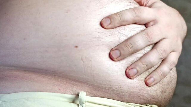 Guy examines his big belly. Concept of body positivity and weight gain during sedentary work. Stock video of male belly in full hd.