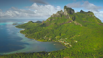 Breathtaking aerial view of Bora Bora island lagoon showing its lush green vegetation, turquoise...