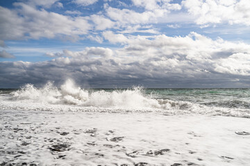 Seascape of stormy Black Sea with rolling foam waves on the seacoast with a cumulonimbus cloud. Waves with white foam crash on a stone ashore. Nature background. Landscape wallpapers.