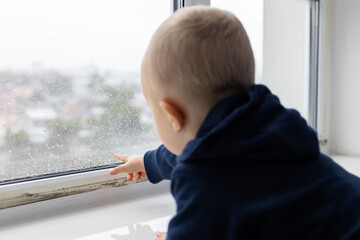 Little child point on condensate water drops on the window glass. Black spots of mouldy fungus on...