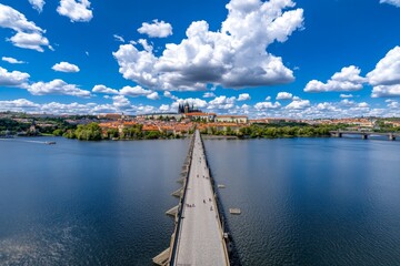 Obraz premium A majestic view of Prague Castle in the Czech Republic, with the Charles Bridge and Vltava River below at sunset