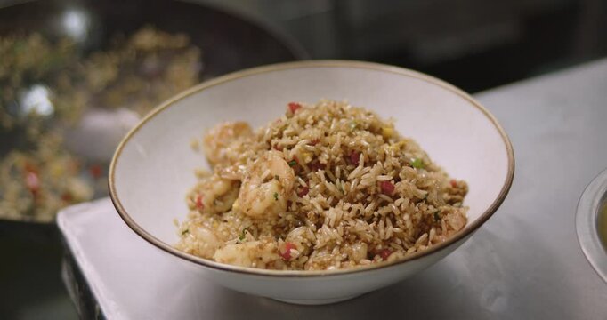 Closeup footage of a chef serving the Peruvian Chaufa Rice with Seafood on a white bowl