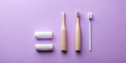 Hygiene essentials flat lay wooden and plastic toothbrushes, and two rolls of toothpaste on a lilac background