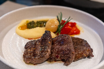Juicy grilled beef served with creamy mashed potatoes, roasted tomatoes, and garnished with herbs.