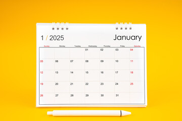 January 2025, Monthly desk calendar for 2025 year and pen on yellow background.