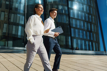 Professionals walking outside a modern office building during daylight on a clear blue sky